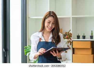 Young Asian Woman Startup Small Business Freelance Sitting With Parcel Box And Computer Laptop On Wood Table In Living Room At Home, Online Marketing Packing Box Delivery Concept