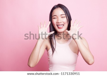 Young Asian woman sticking her  tongue out on pink background