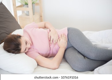 Young asian woman suffering from abdominal pain on the bed. - Shutterstock ID 1076191016