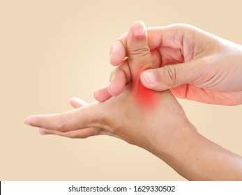 Young Asian woman suffering sore hand, wrist, finger pain and massaging on thumb finger, isolated on brown background. medical symptom and healthcare concept.