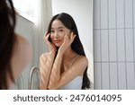 Young Asian woman taking care of her skin in front of a mirror