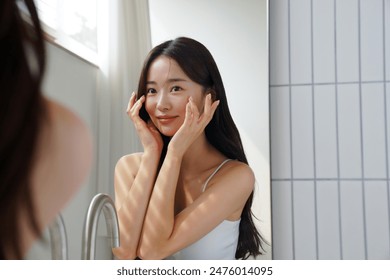 Young Asian woman taking care of her skin in front of a mirror - Powered by Shutterstock