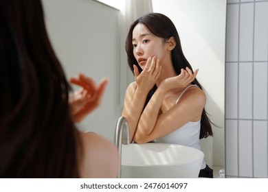 Young Asian woman taking care of her skin in front of a mirror