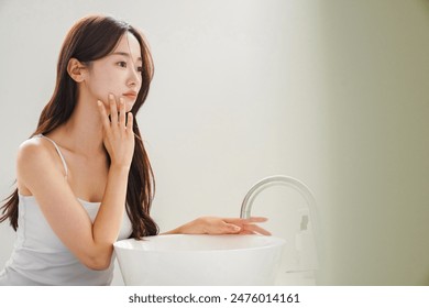 Young Asian woman taking care of her skin in front of a mirror - Powered by Shutterstock