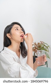 Young Asian Woman Is Taking Medicine In Living Room
