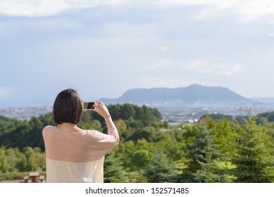Young Asian woman taking photo of landscape of Hakodate, Hokkaido, Japan.
