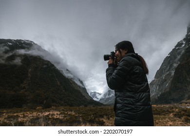 Young asian woman taking photo with digital camera during cloudy and rainy day - Powered by Shutterstock