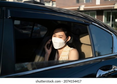 Young Asian Woman Talking On Mobile Phone While Sitting In A Taxi.