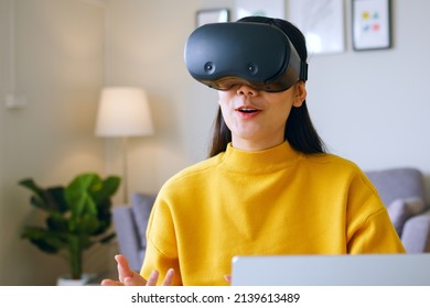 Young Asian Woman Talking While Using 360 VR Headset For Online Meeting In Metaverse At Home 