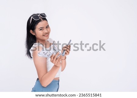 A young asian woman teasing to give you some cash. Showing off dollar bills to the camera. Isolated on a white background.