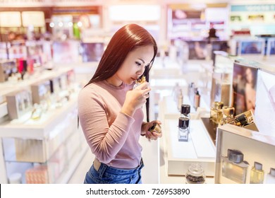 Young asian woman testing and choose to buy perfume in duty free store at international airport.