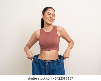 Young asian woman thin slender abdomen waist wearing old big jean after her success weight loss diet session. Care about eating and workout exercise for slim fit and firm good shape - Powered by Shutterstock