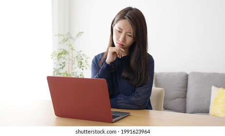young asian woman thinking using laptop in the living room - Shutterstock ID 1991623964