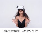 A young asian woman is thrilled while navigating a VR environment via a virtual reality headset. Isolated on a white backdrop.