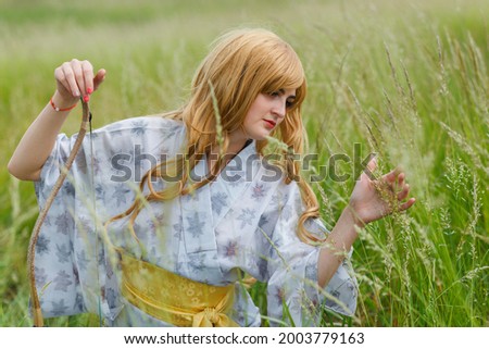 Young asian woman in traditional kimono trains fighting techniques with Samurai Bow outdoors, samurai warrior girl
