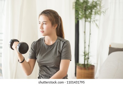 Young Asian Woman Training With Dumbell At Home. Fitness And Healthy Lifestyle Concept