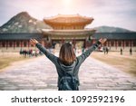 Young asian woman traveler with backpack traveling into the Gyeongbokgung Palace  with blue sky and clouds at Seoul city, South Korea.