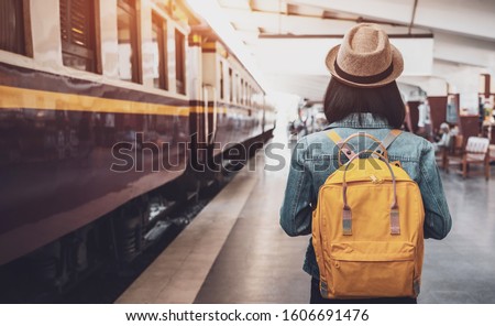 Young asian woman traveler with backpack in the railway, Backpack and hat at the train station with a traveler, Travel concept. Woman traveler tourist walking at train station Foto d'archivio © 
