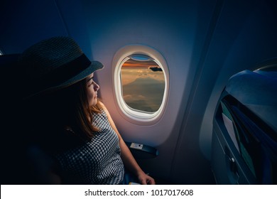 Young asian woman traveler looking view at window in airplane with happiness and relaxing