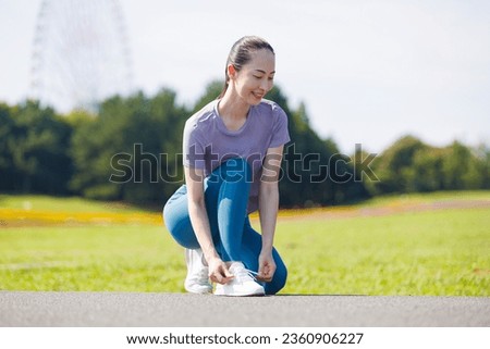 Young Asian woman tying shoelace at the park