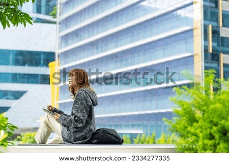 Young Asian woman university college student walking in the city working e-learning creative designer study class project or freelance work anywhere job on tablet and digital pen with online network.