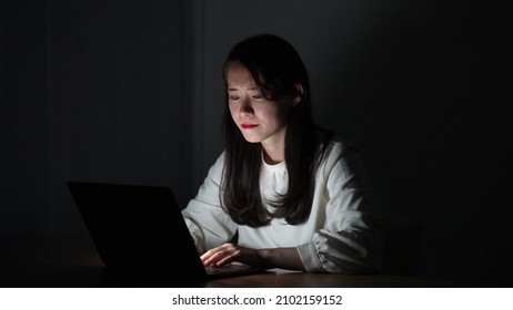 Young Asian Woman Using Computer In A Dark Room