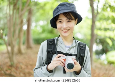 Young Asian Woman Using Digital Camera In A Forest