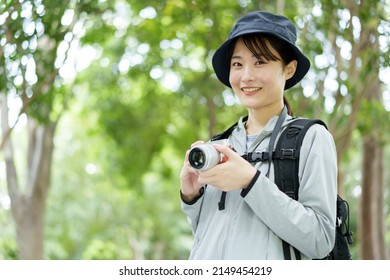 Young Asian Woman Using Digital Camera In A Forest