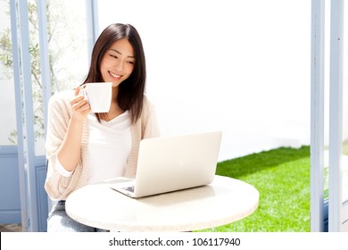 A Young Asian Woman Using Laptop Compute In Cafe