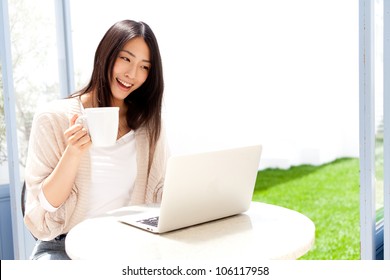 A Young Asian Woman Using Laptop Compute In Cafe