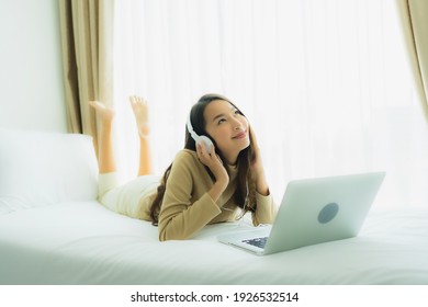 Young asian woman using laptop with headphone for listen music in bedroom interior - Shutterstock ID 1926532514