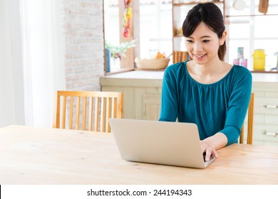 Young Asian Woman Using Laptop Computer In The Kitchen