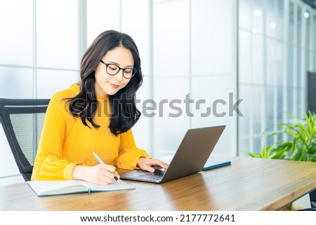Young Asian woman using a laptop PC in modern office.