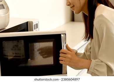 Young Asian woman using a microwave

