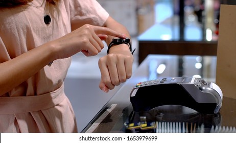 Young Asian Woman Using Mobile Phone - Smartwatch To Purchase Product At The Point Of Sale Terminal In A Retail Store With Near Field Communication Nfc  Radio Frequency Identification Payment