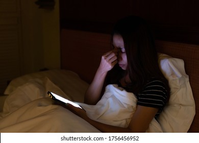 Young Asian Woman Using Mobile Phone At Night And Feeling Eye Pain And Dry. Eye Strain Tension Or Blurry Vision Problem Concept