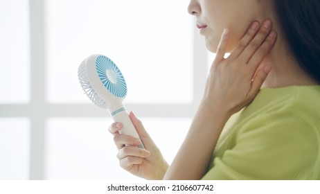 Young Asian woman using a portable fan. - Shutterstock ID 2106607742