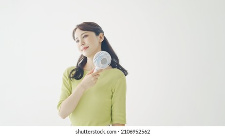 Young Asian Woman Using A Portable Fan.