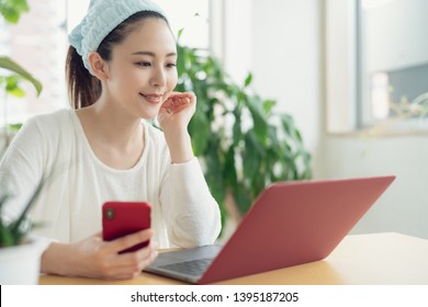Young asian woman using a smart phone and a laptop comuter.
