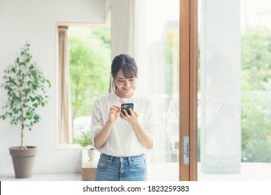 Young Asian Woman Using A Smart Phone In The Room.