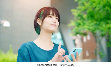 Young asian woman using a smart phone at outdoors.
