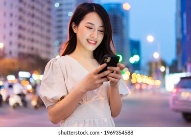 Young Asian woman using smartphone on the street at night