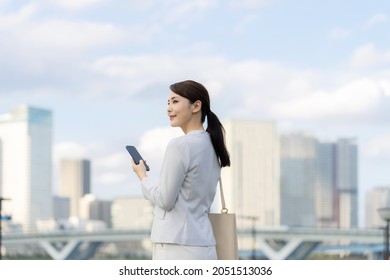 Young Asian Woman Using A Smartphone In Front Of The City.