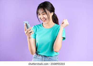 Young Asian woman using smartphone on purple background