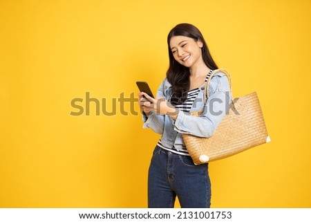 Young Asian woman using smartphone and receiving good news from the message on mobile chat application over yellow background, Wow and surprised concept