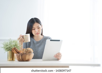 Young Asian Woman Using Tablet At Home And Having Breakfast In The Morning .She Reading On Tablet.