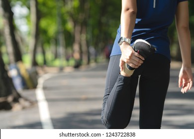 Young Asian Woman Warm Up Before Workout Or Cool Down After Running In Nature Public City Park. Cardio Sport For Weight Lose In Millennial Runner Concept. Girl Stretching And Exercise Before Jogging.