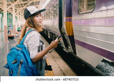 Young Asian Woman Watching The Train Schedule Waiting To Board The Train As Vintage Tone, Travel Concept