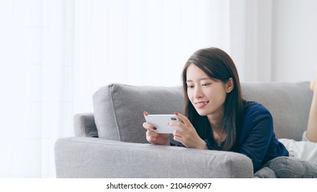 Young asian woman watching video with a smart phone. - Shutterstock ID 2104699097