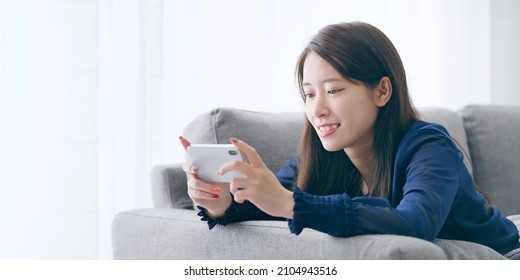 Young asian woman watching video with a smart phone. - Shutterstock ID 2104943516